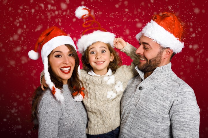 Young family dressed with winter clothes and santa hat